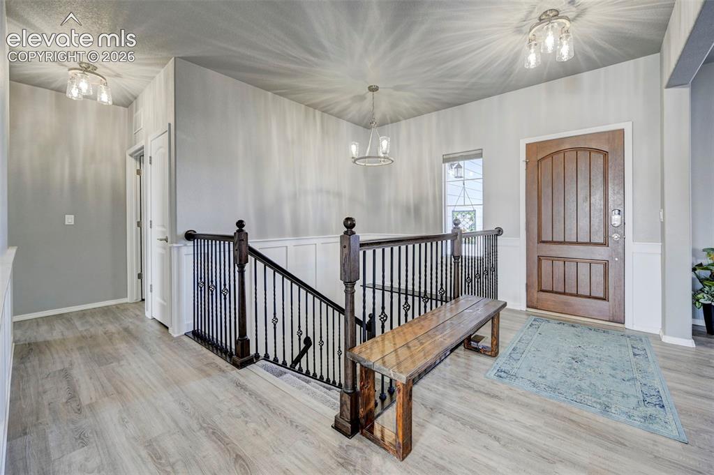 Image 19 of 48: Entryway featuring wood-finish flooring, wainscoting, and a wood entry door