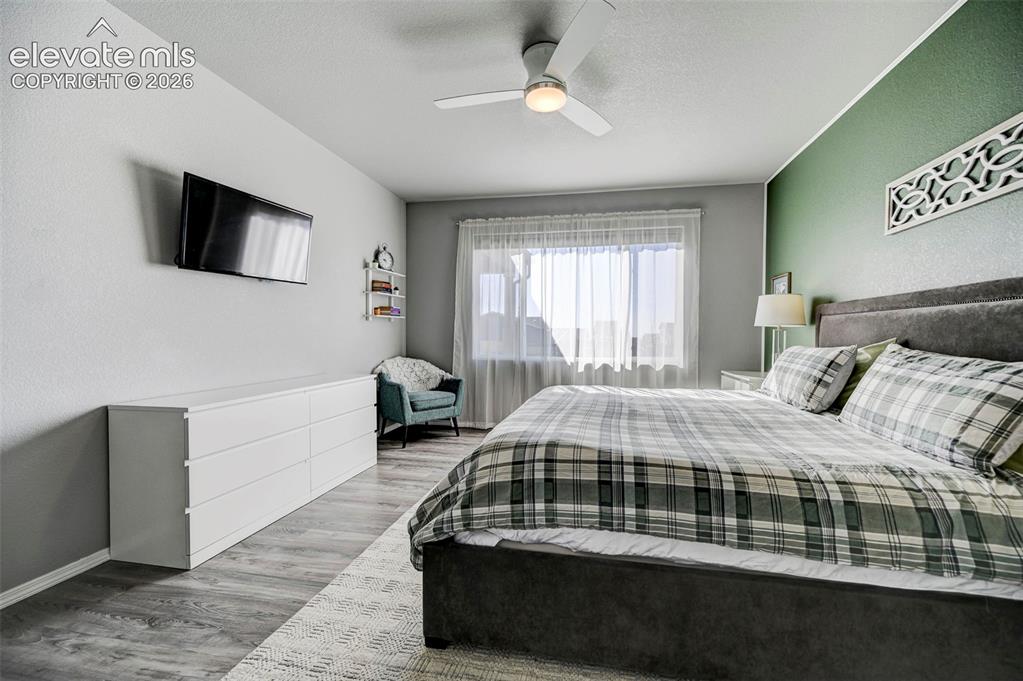 Image 21 of 48: Bedroom featuring a textured accent wall, wood-finish flooring, and a ceili