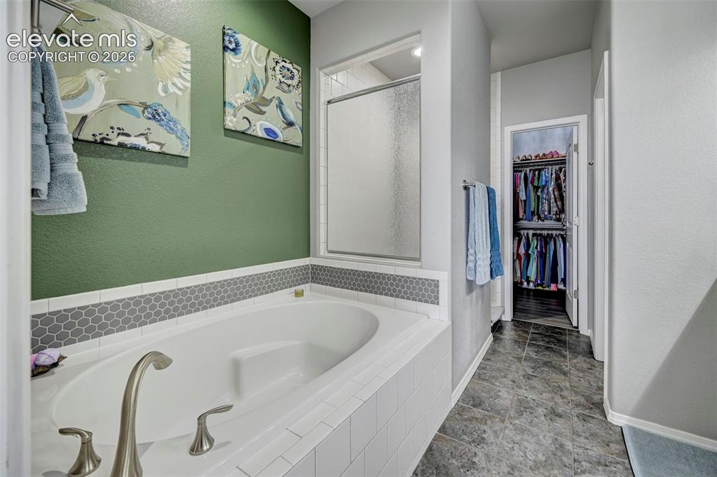 Image 22 of 48: Soaking tub with brushed nickel fixtures and a tiled surround