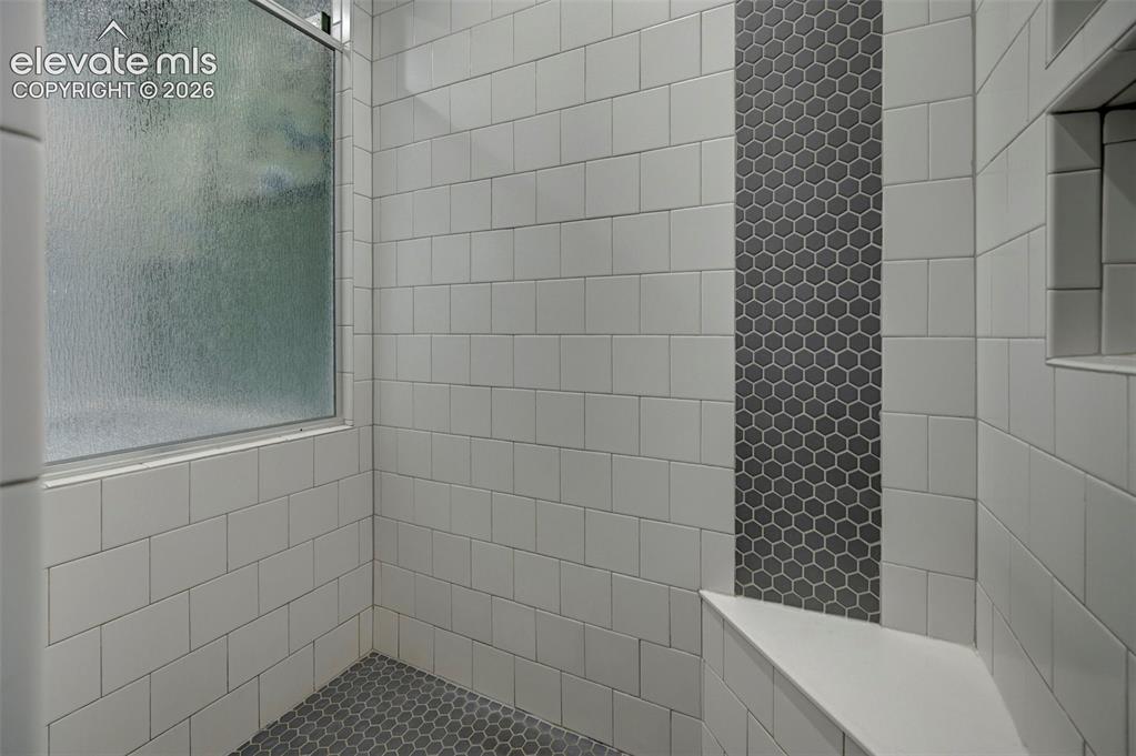 Image 25 of 48: Shower enclosure featuring white subway tile, a frosted window, a dark hexa