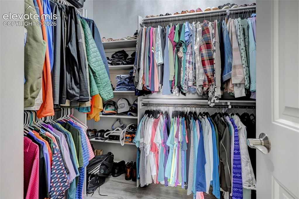 Image 26 of 48: Walk-in closet featuring multiple clothing rods, integrated shelving, and w