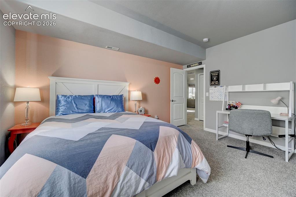 Image 27 of 48: Carpeted room featuring a white paneled headboard and a dedicated workspace