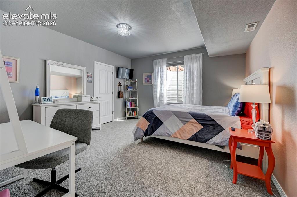 Image 28 of 48: Carpeted room featuring a window with blinds and white sheer curtains, a wh
