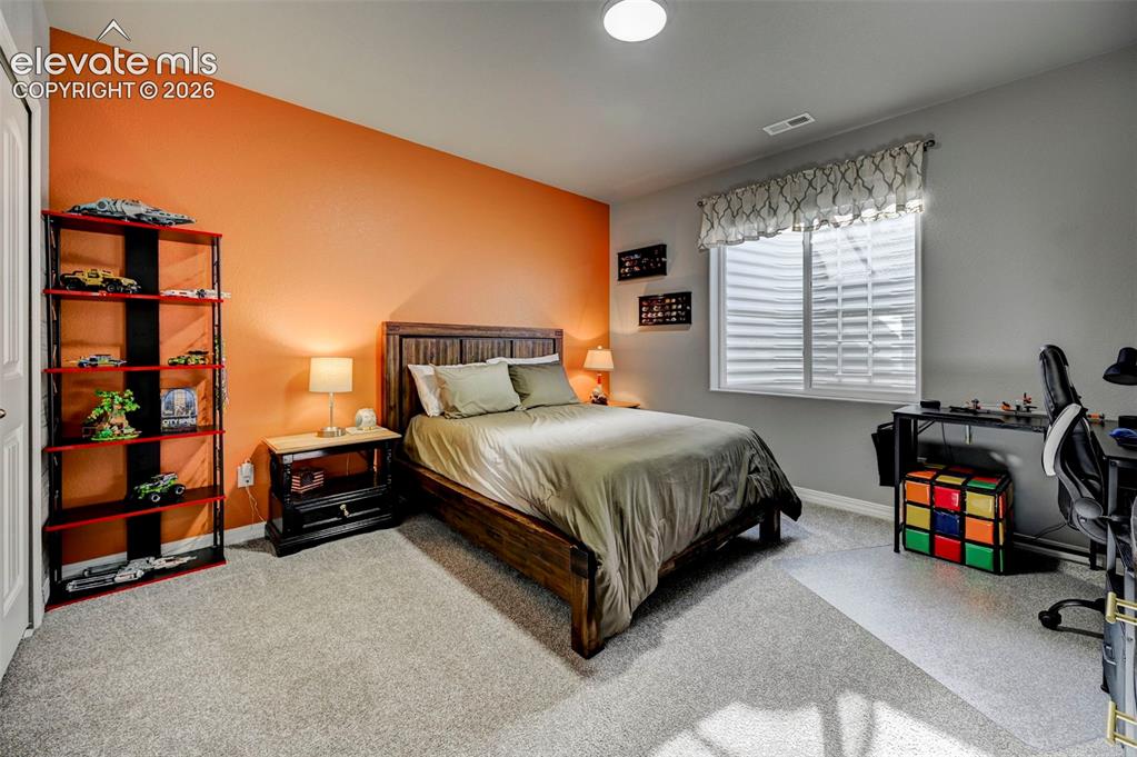 Image 31 of 48: Bedroom featuring light gray carpet flooring and a statement wall in orange