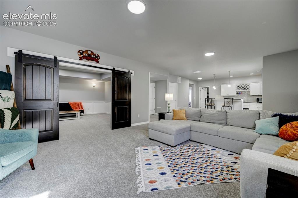 Image 36 of 48: Spacious living area featuring light gray walls, recessed lighting, and a n