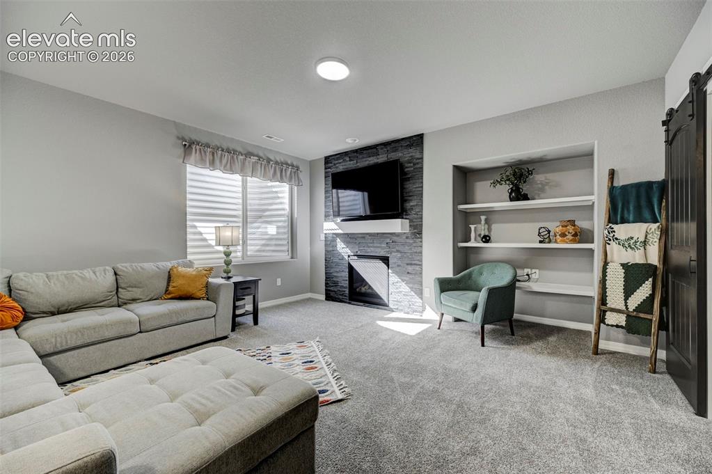 Image 37 of 48: Living area featuring a stone-clad fireplace with a white mantel, recessed
