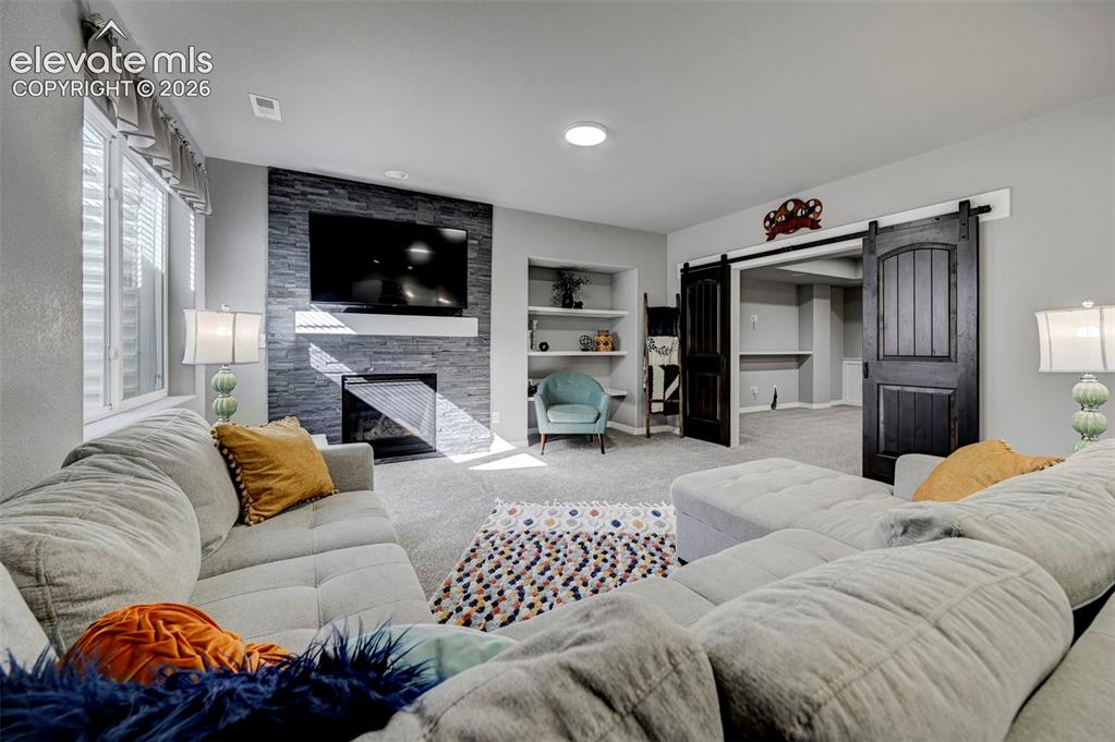 Image 38 of 48: Spacious living area featuring a stacked stone fireplace with a floating ma