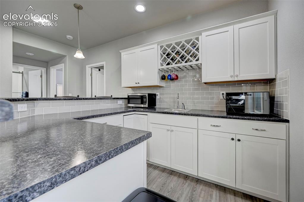 Image 39 of 48: Contemporary kitchen with white shaker-style cabinetry, granite-patterned c