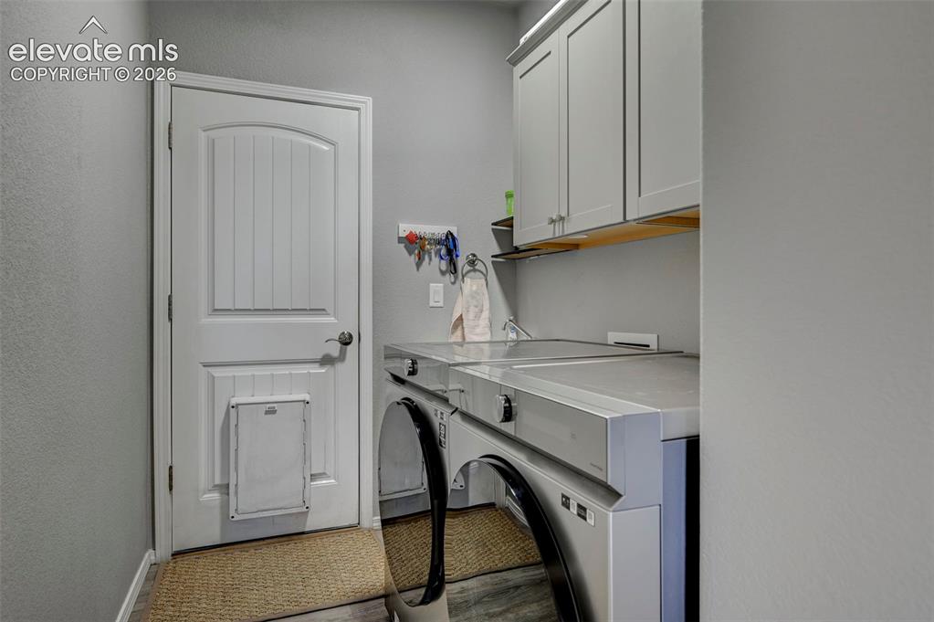 Image 42 of 48: Laundry area with shaker-style upper cabinetry, an integrated countertop, a