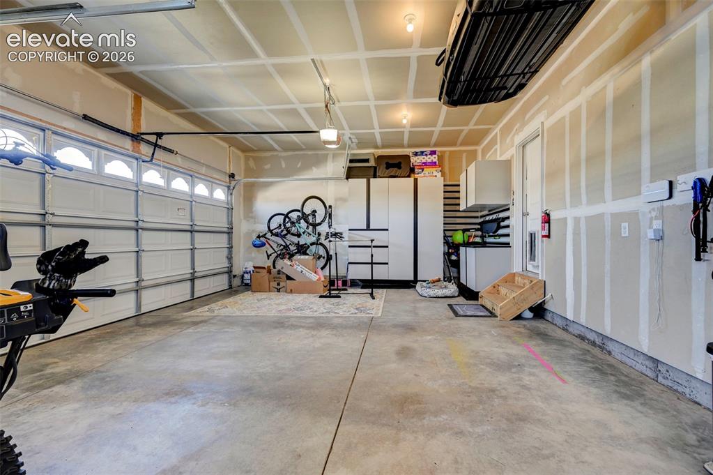 Image 47 of 48: Spacious garage featuring a concrete floor, two overhead garage doors with