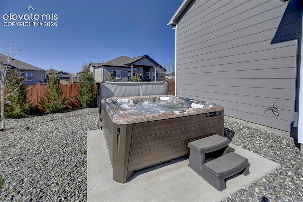 Image 6 of 48: Outdoor spa on a concrete pad, surrounded by grey gravel landscaping