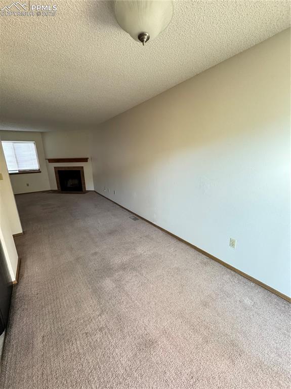 Image 3 of 11: Unfurnished living room featuring a fireplace with flush hearth, carpet, an