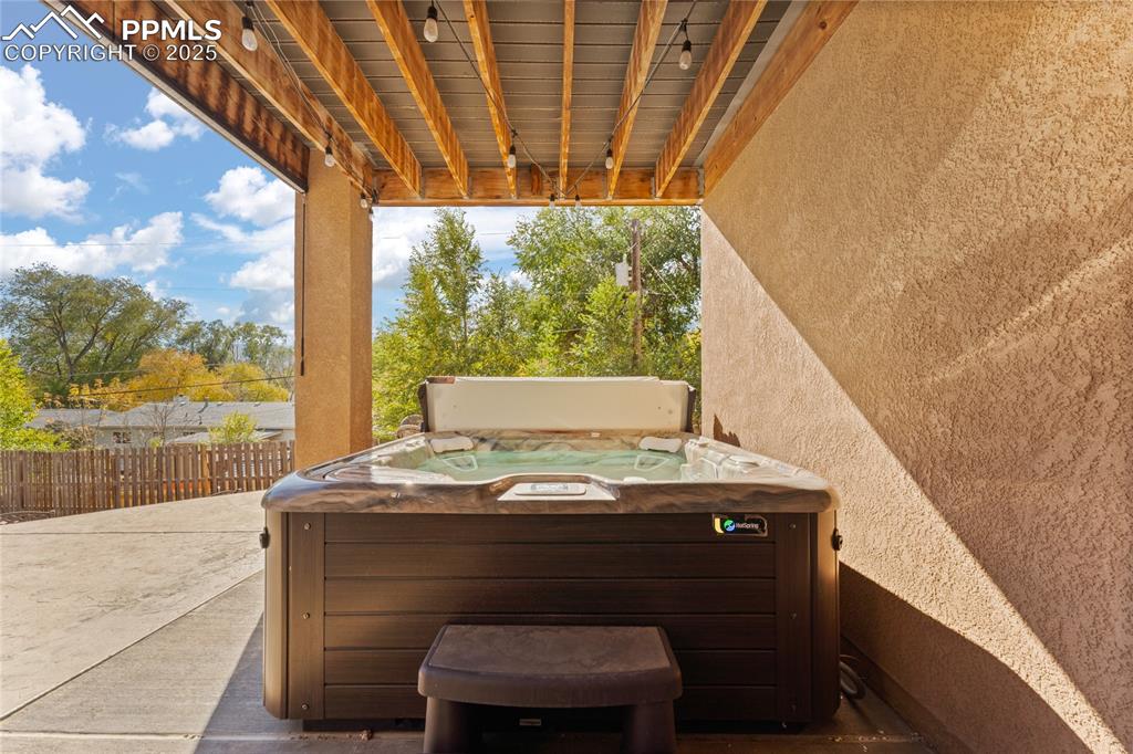 Image 37 of 41: Stamped Concrete Patio with Salt Water Hot Tub. Pull Down Blinds for Privac