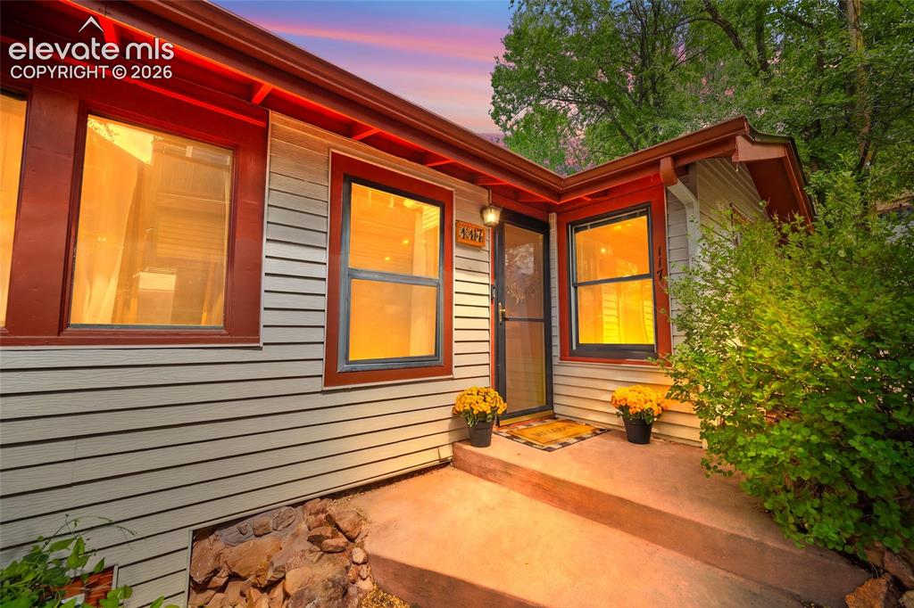Image 1 of 31: Charming twilight curb appeal at this Manitou Springs cottage, featuring wa