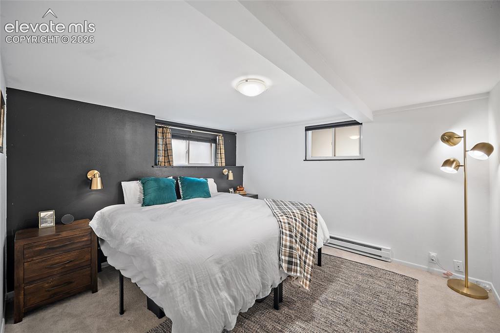 Image 15 of 31: Cozy lower-level bedroom with a striking charcoal accent wall, brass sconc