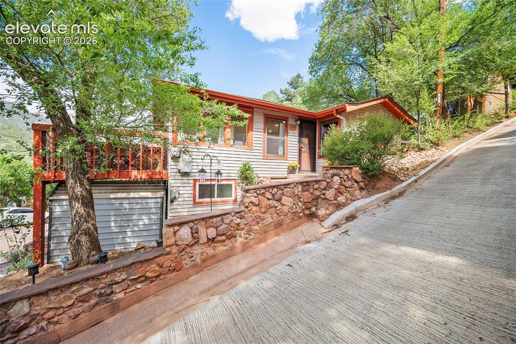 Image 29 of 31: Picturesque hillside setting with concrete driveway, natural stone retainin
