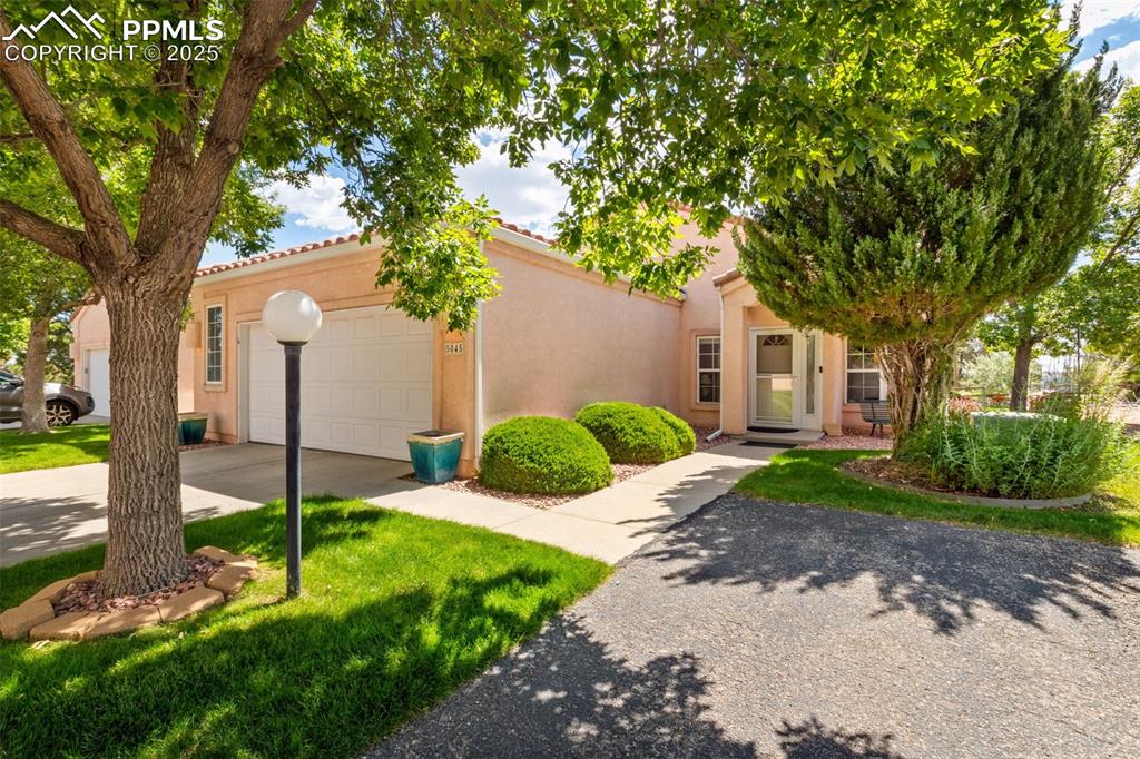 Caption: View of front of property with driveway, stucco siding, and an attached garage