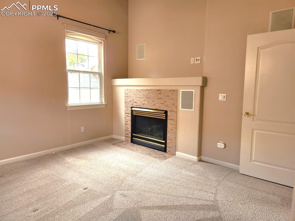 Image 11 of 34: Unfurnished living room with a fireplace with flush hearth and carpet floor