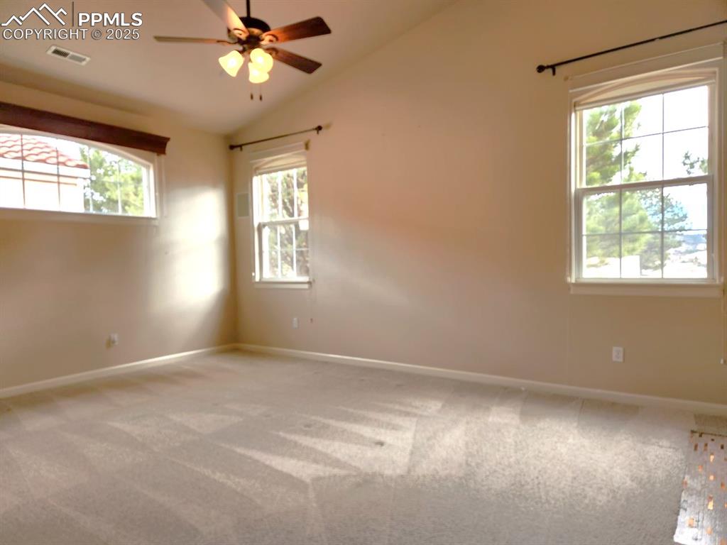 Image 12 of 34: Unfurnished room with light carpet, ceiling fan, and vaulted ceiling