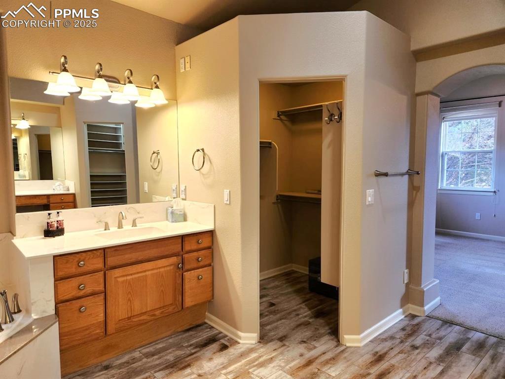 Image 15 of 34: Bathroom featuring a walk in closet, vanity, and wood finished floors