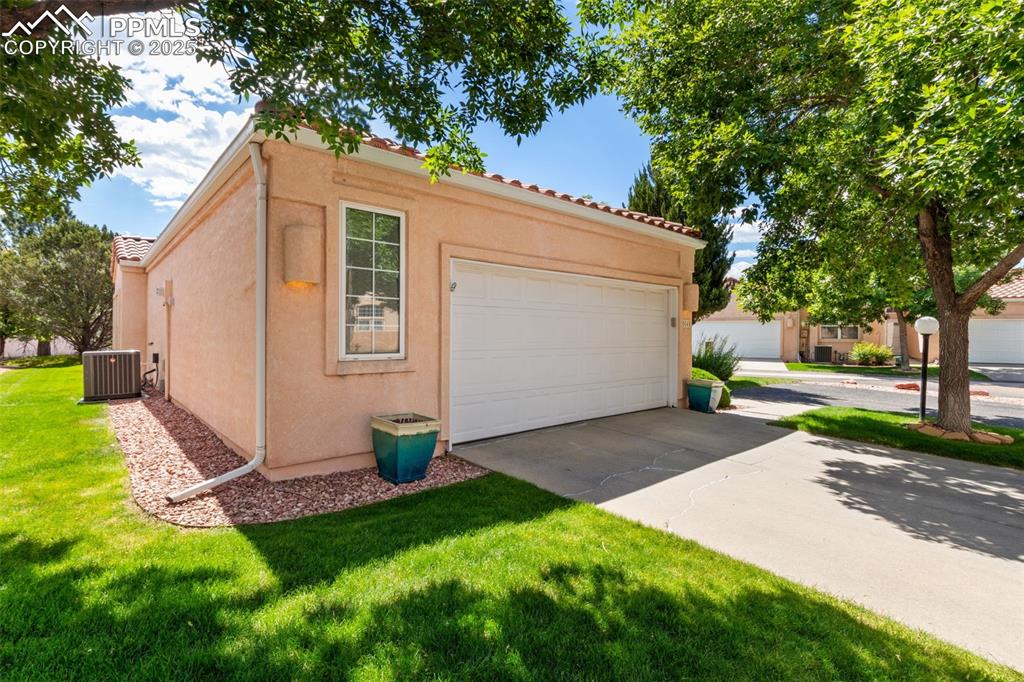 Image 2 of 34: View of front facade featuring stucco siding, driveway, a front yard, and a