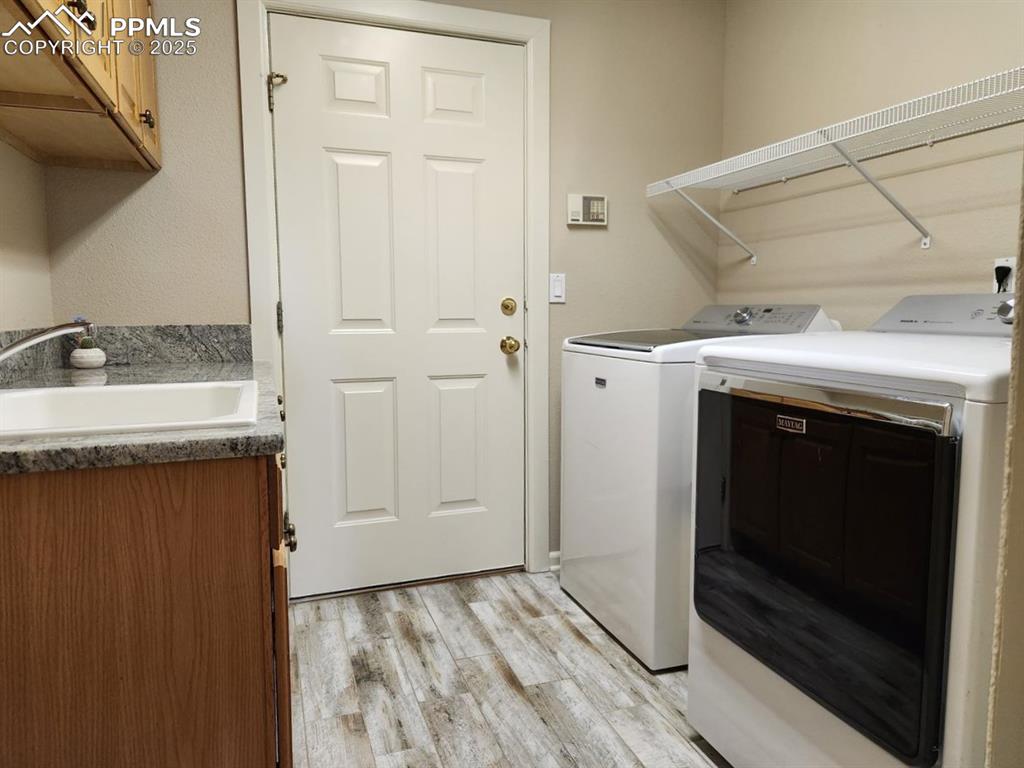 Image 23 of 34: Laundry room featuring washing machine and dryer, light wood-type flooring,