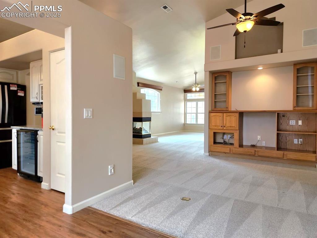 Image 8 of 34: Unfurnished living room featuring wine cooler, ceiling fan, and a multi sid