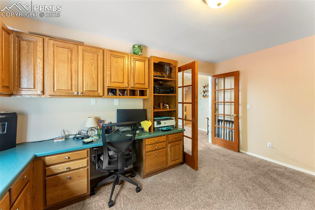 Image 14 of 50: Office area featuring built in study area, light colored carpet, and french