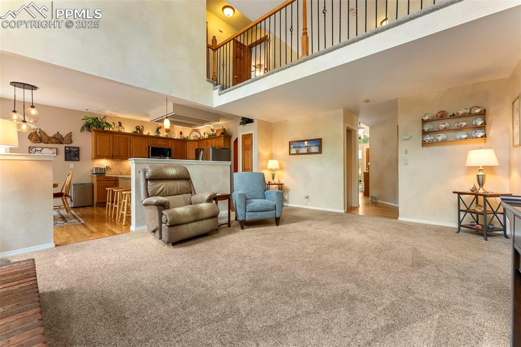Image 15 of 50: Living area featuring light carpet and a towering ceiling