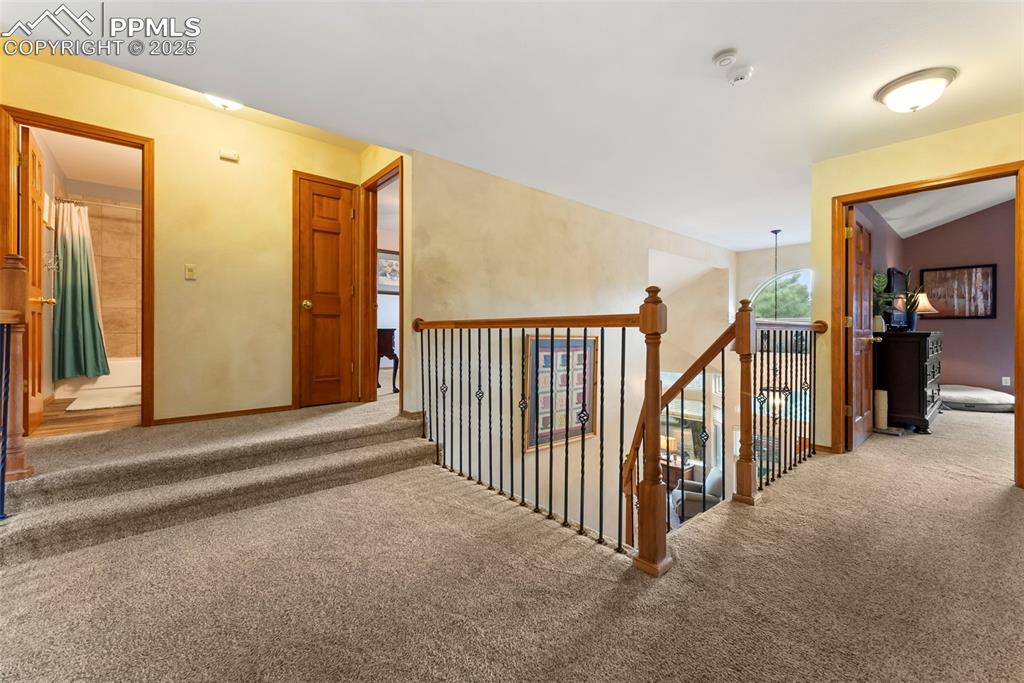 Image 23 of 50: Hallway featuring carpet flooring and an upstairs landing