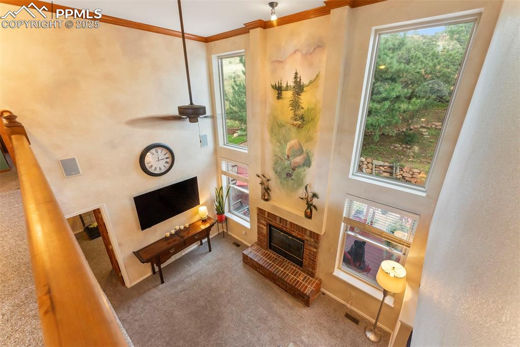 Image 24 of 50: Carpeted living area with a brick fireplace, a towering ceiling, ornamental