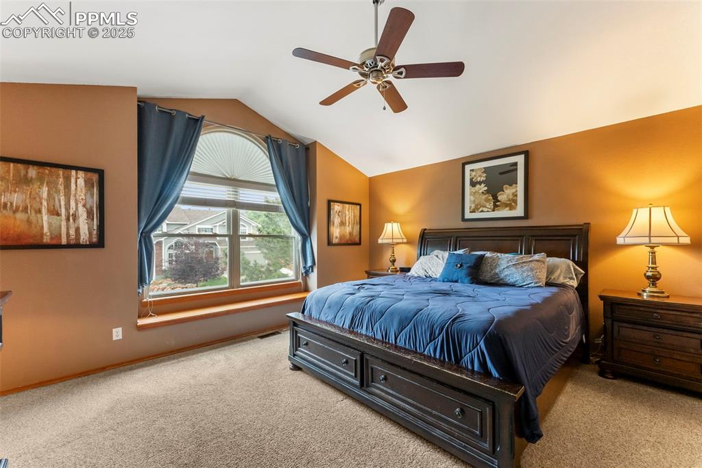 Image 25 of 50: Carpeted bedroom with vaulted ceiling and a ceiling fan