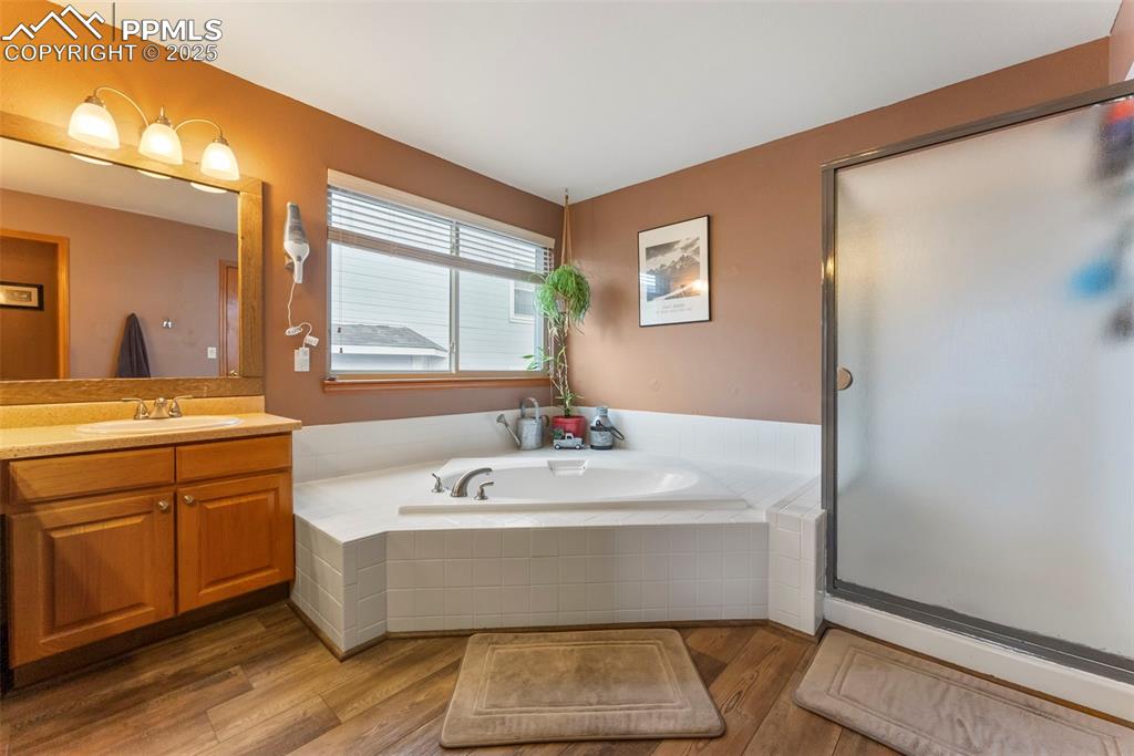 Image 28 of 50: Full bath with vanity, a garden tub, dark wood-style floors, and a shower s