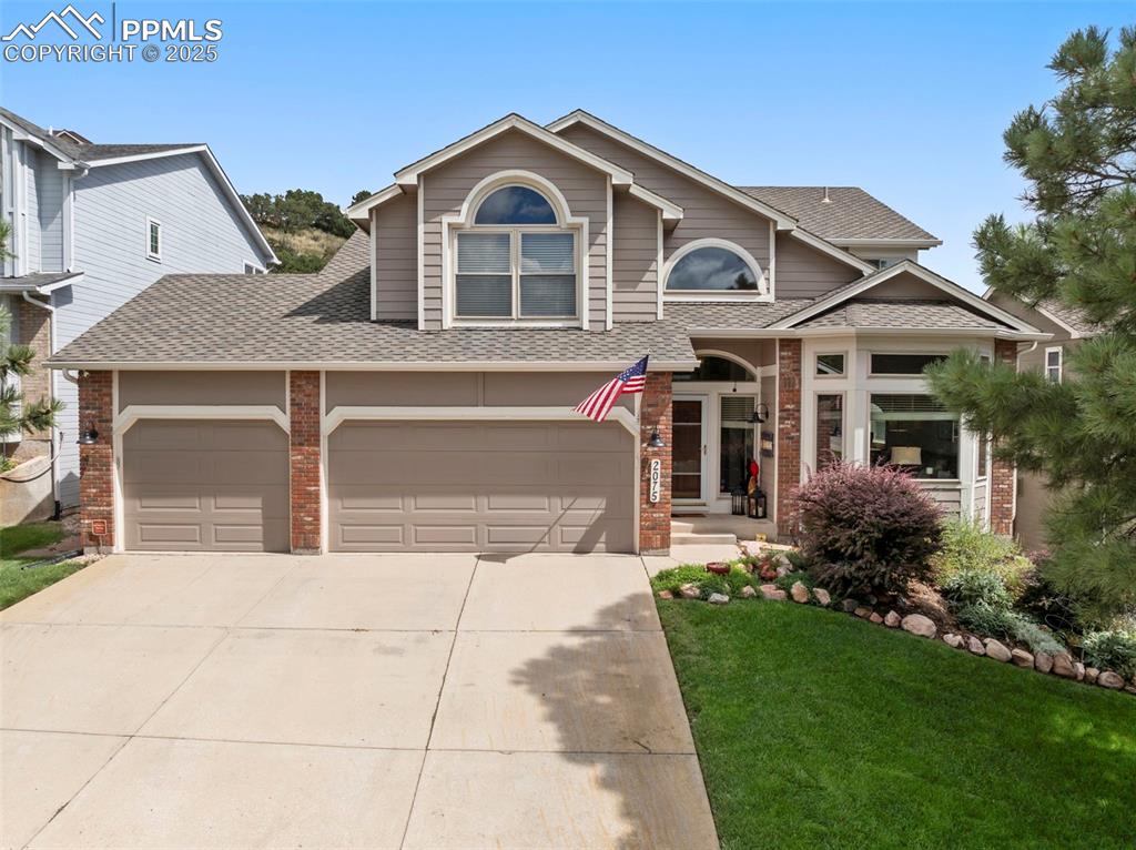Image 3 of 50: View of front of house featuring roof with shingles, brick siding, driveway