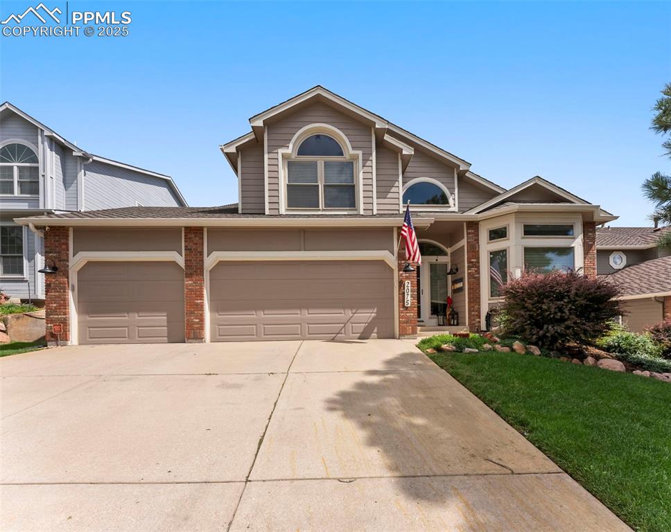 Image 4 of 50: View of front facade with brick siding, concrete driveway, and roof with sh
