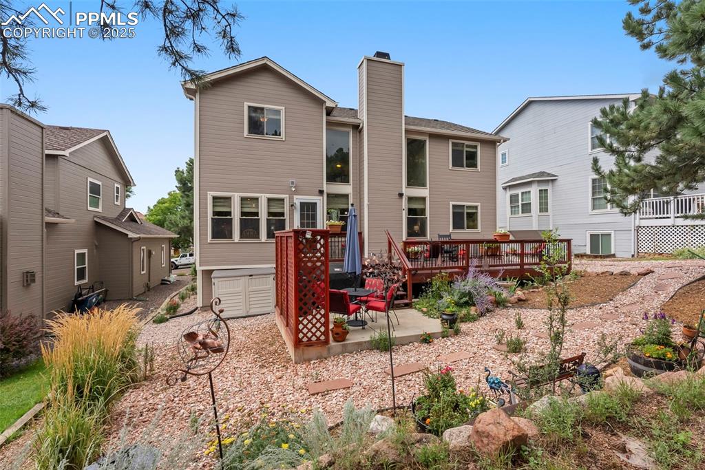 Image 42 of 50: Rear view of house with a chimney, a wooden deck, and a patio