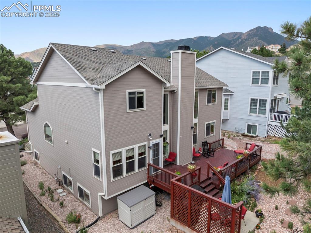 Image 45 of 50: Back of property with a deck with mountain view, a chimney, a shingled roof
