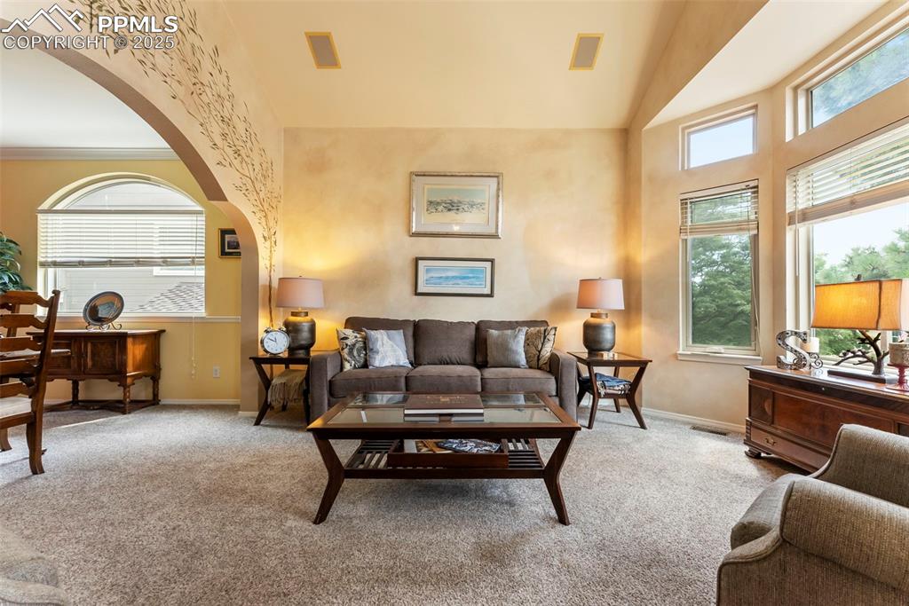 Image 5 of 50: Living room featuring arched walkways, light colored carpet, and high vault