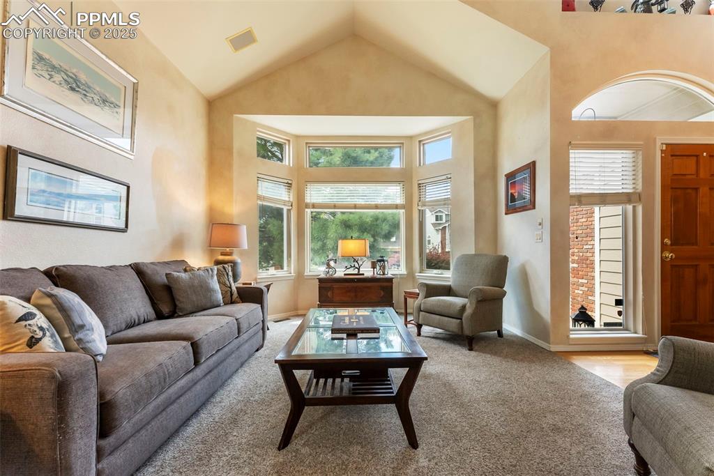 Image 6 of 50: Carpeted living area with high vaulted ceiling and baseboards