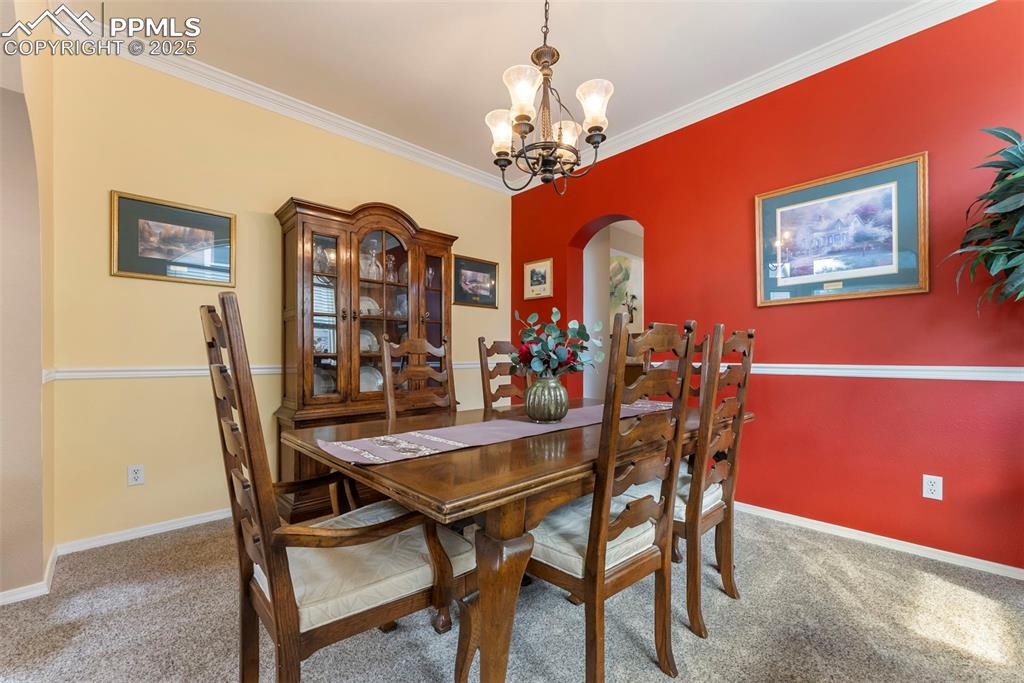 Image 8 of 50: Dining area with arched walkways, light carpet, a chandelier, and ornamenta