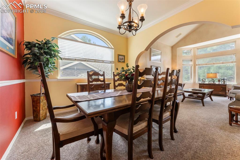 Image 9 of 50: Dining area with light carpet, ornamental molding, arched walkways, a chand