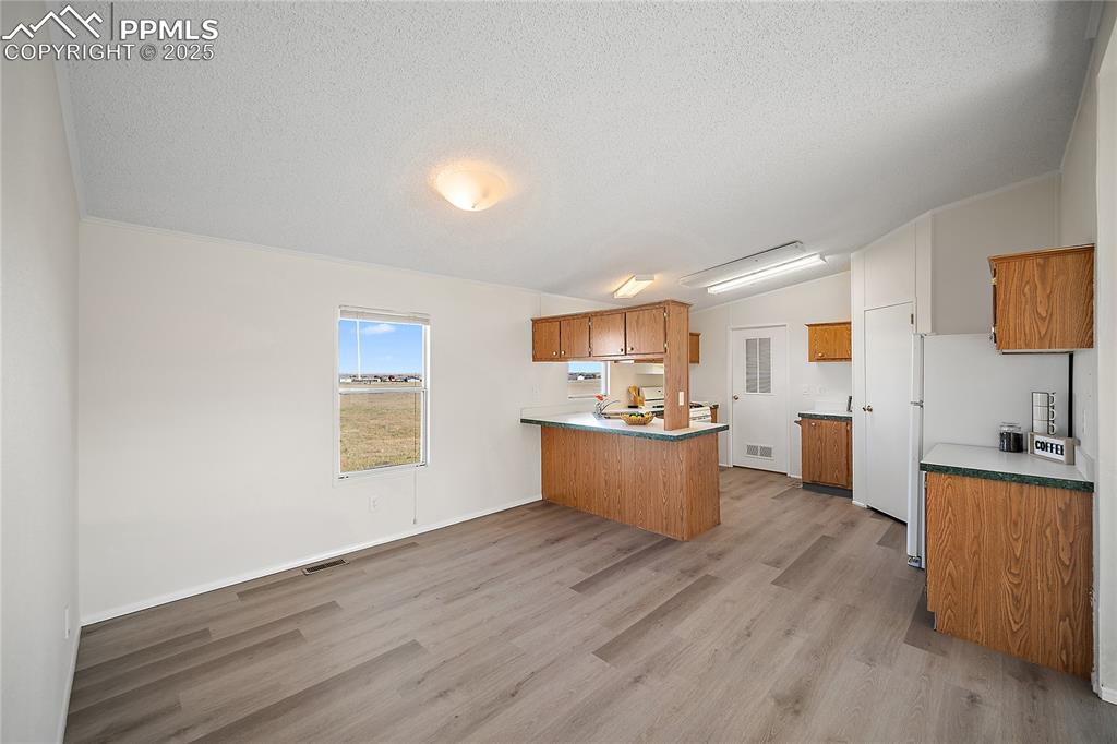 Image 15 of 34: Dining and kitchen with new laminate flooring and vaulted ceilings. 