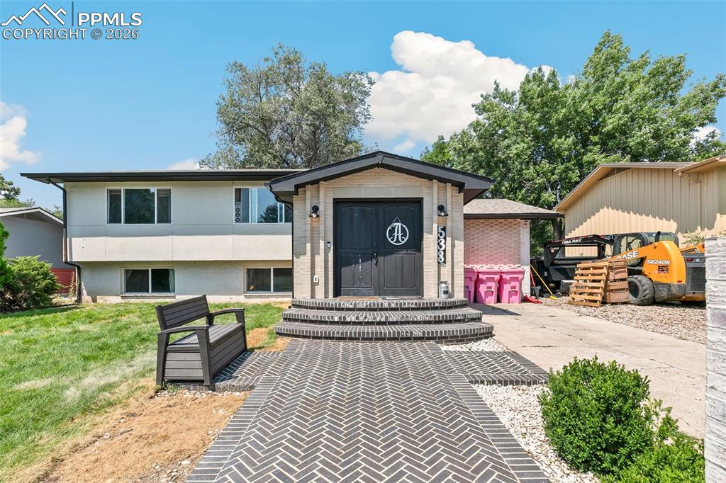Caption: View of front facade featuring brick siding and a front yard