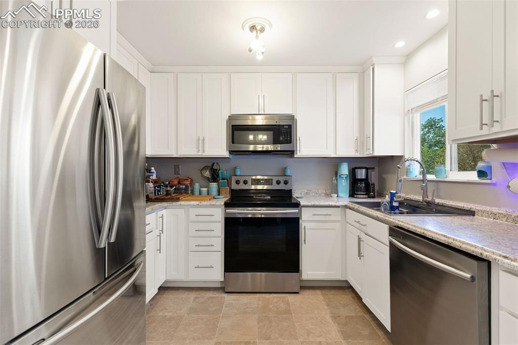 Image 13 of 38: Kitchen with stainless steel appliances, white cabinetry, and recessed ligh