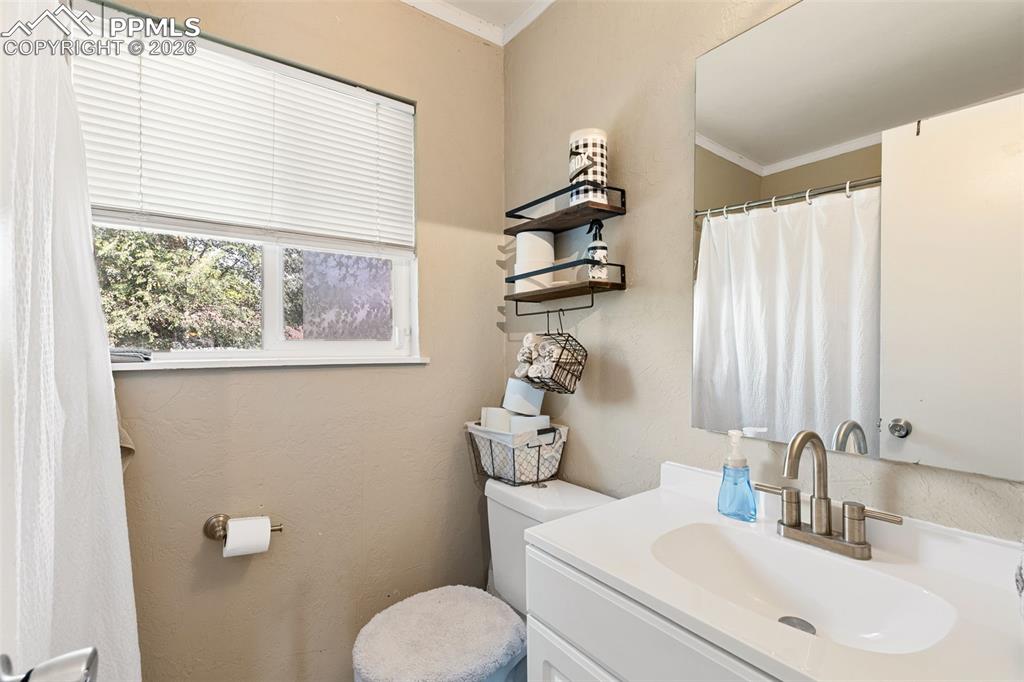 Image 19 of 38: Full bathroom with vanity, ornamental molding, and a textured wall