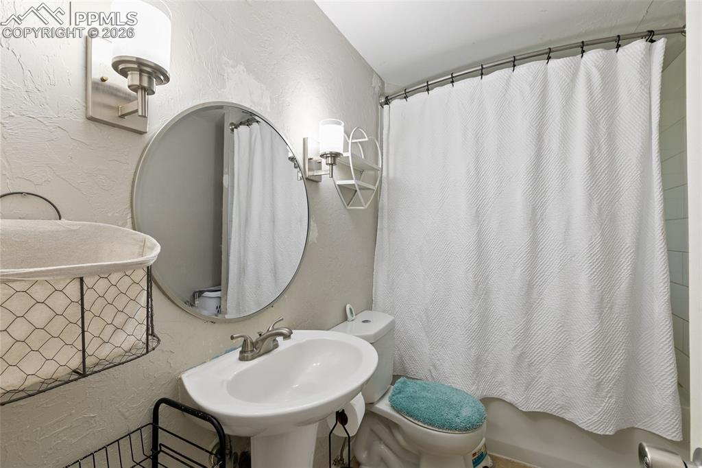 Image 30 of 38: Full bathroom featuring a textured wall and shower / bath combination with