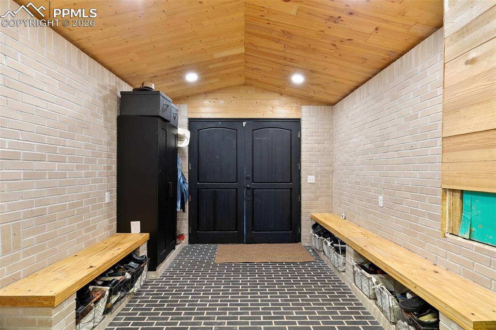 Image 5 of 38: Mudroom with brick wall, wood ceiling, brick flooring, vaulted ceiling, and
