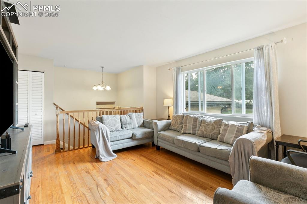Image 8 of 38: Living room with light wood-type flooring and a chandelier