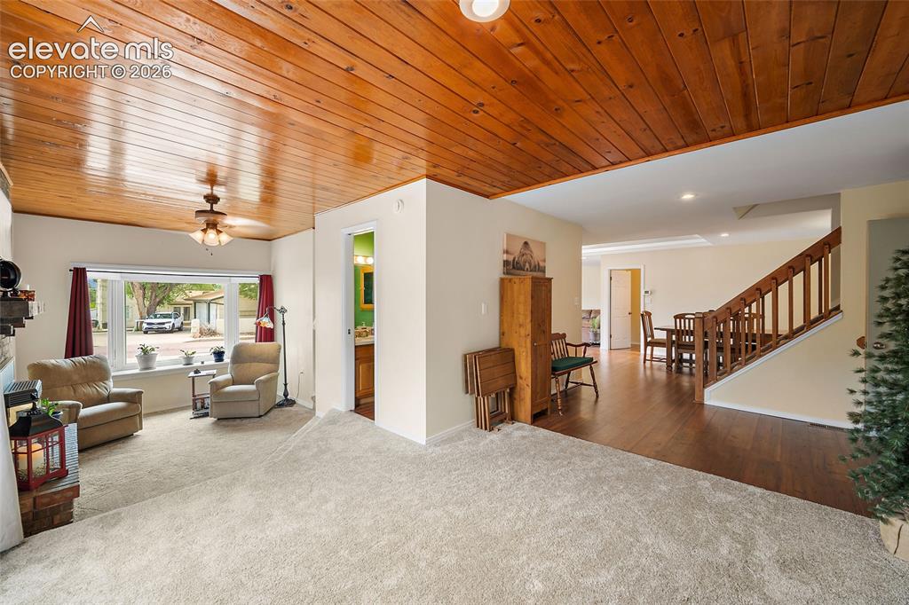 Image 13 of 44: Spacious living area featuring a wood-panel ceiling, plush carpeting, a lar