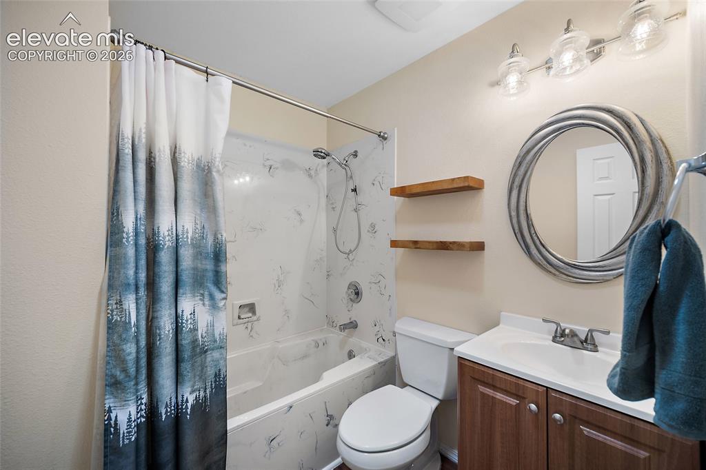 Image 17 of 44: Full bathroom featuring a single vanity with wood-finish cabinetry, a white